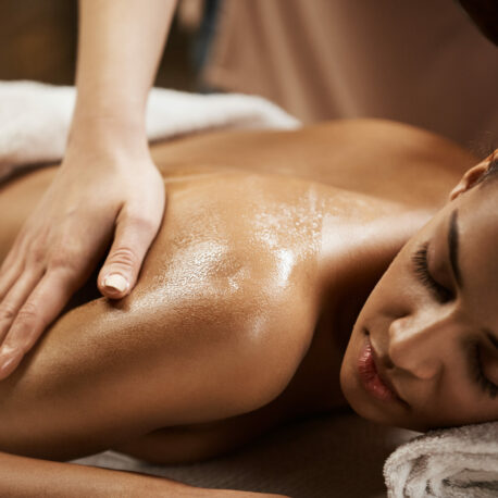 Close up photo of beautiful african girl enjoying massage in spa salon.